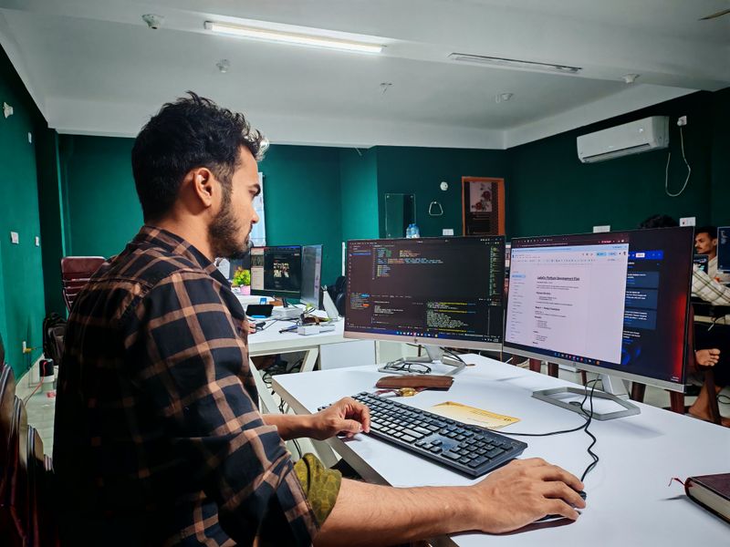 A developer working at a desk with two monitors showing code