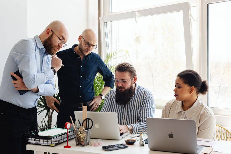 A team of four planning a project around laptops in a bright office